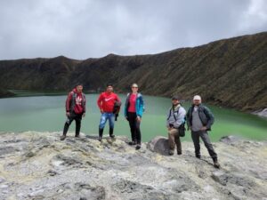 Group standing on a lava dome in with the Azfrual Crater in Colombia in the background.